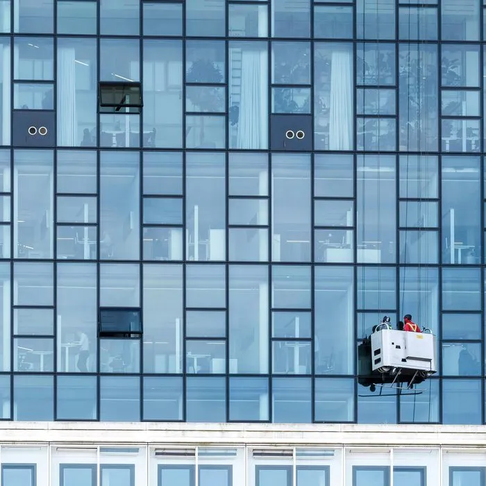 Die Glasfassade eines Bürohochhauses mit der Arbeitsbühne von Fensterputzern