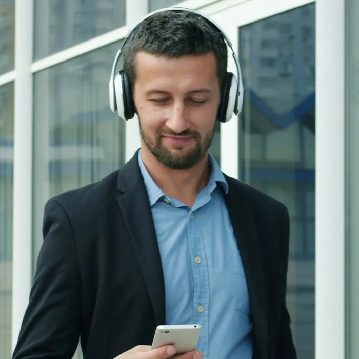 Ein Mann mit Kopfhörern um den Hals liest auf seinem Smartphone