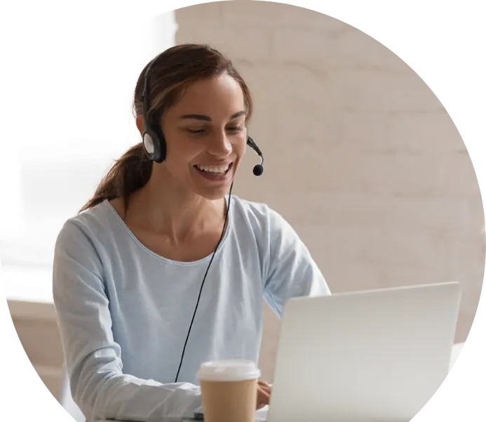 Eine lächelnde Frau mit Headset arbeitet an einem Laptop