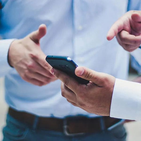 Zwei Personen in Hemden schauen gemeinsam auf ein Smartphone